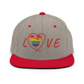 A structured flat-brim baseball cap in heather gray with a bright red brim, red button, and red embroidered 'LOVE' text on the front. The letter 'O' is replaced by a rainbow-striped heart, making this a Pride-themed cap.